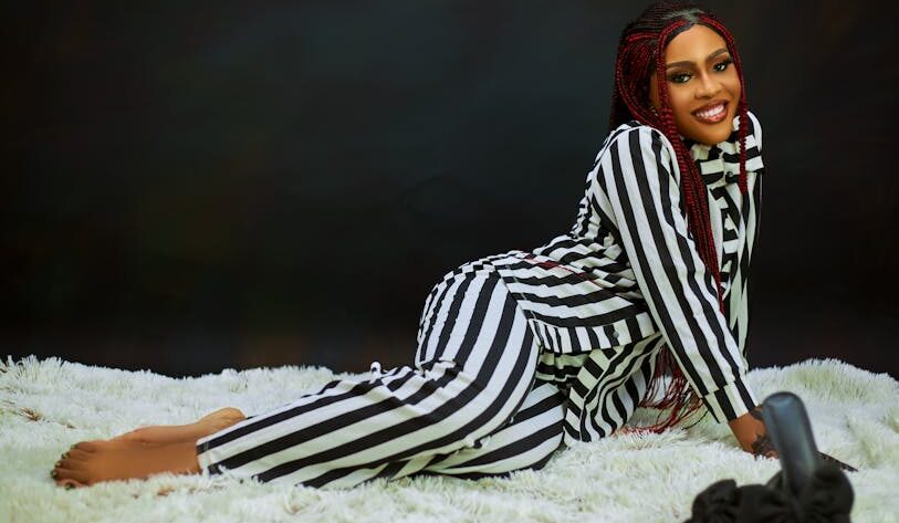 kobieta w ubraniu w czarno-białe paski leżąca na białym shaggy dywanie