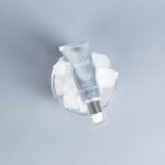 Tubka serum Medik8 Crystal Retinal 6 umieszczona w szklanym naczyniu z kostkami lodu.