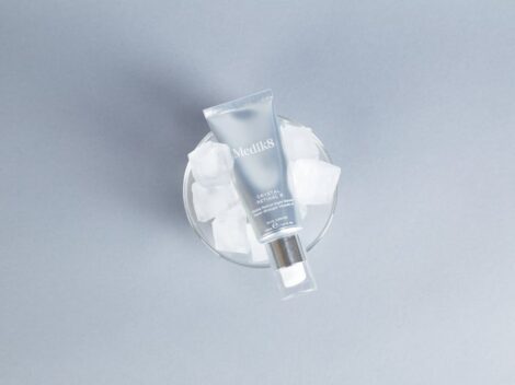 Tubka serum Medik8 Crystal Retinal 6 umieszczona w szklanym naczyniu z kostkami lodu.