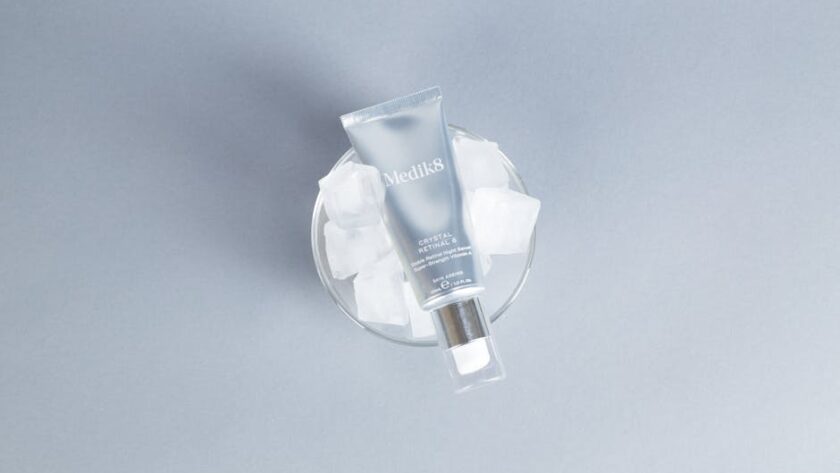 Tubka serum Medik8 Crystal Retinal 6 umieszczona w szklanym naczyniu z kostkami lodu.
