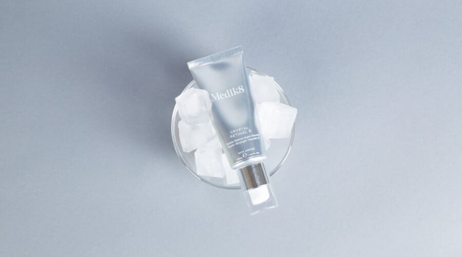 Tubka serum Medik8 Crystal Retinal 6 umieszczona w szklanym naczyniu z kostkami lodu.