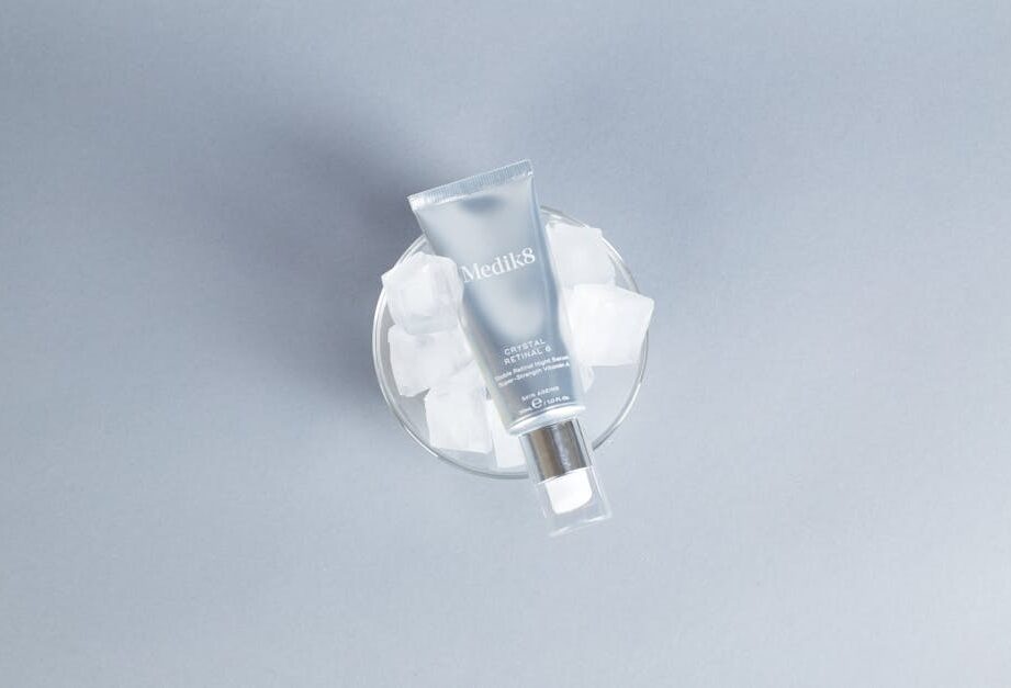 Tubka serum Medik8 Crystal Retinal 6 umieszczona w szklanym naczyniu z kostkami lodu.